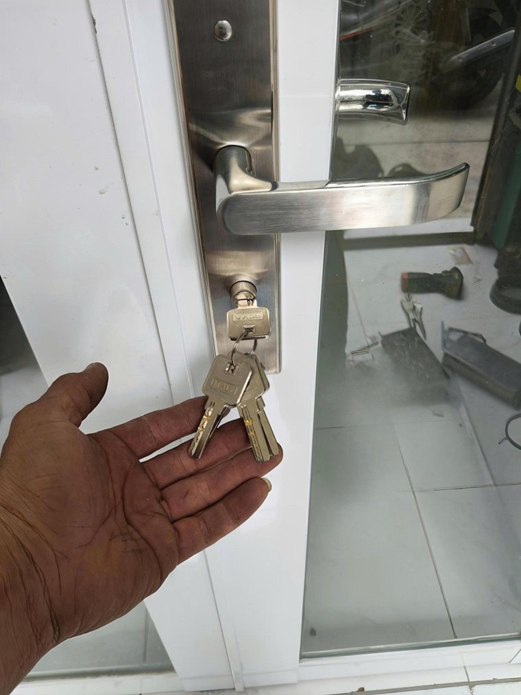 Bộ khóa trên cửa nhôm trắng; cần đối chiếu cả chốt và phần đón trên khung.
